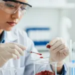 A woman in a lab coat examines red cinnabar pigment.