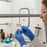 A woman analyzes a TLC plate in a chemistry lab.